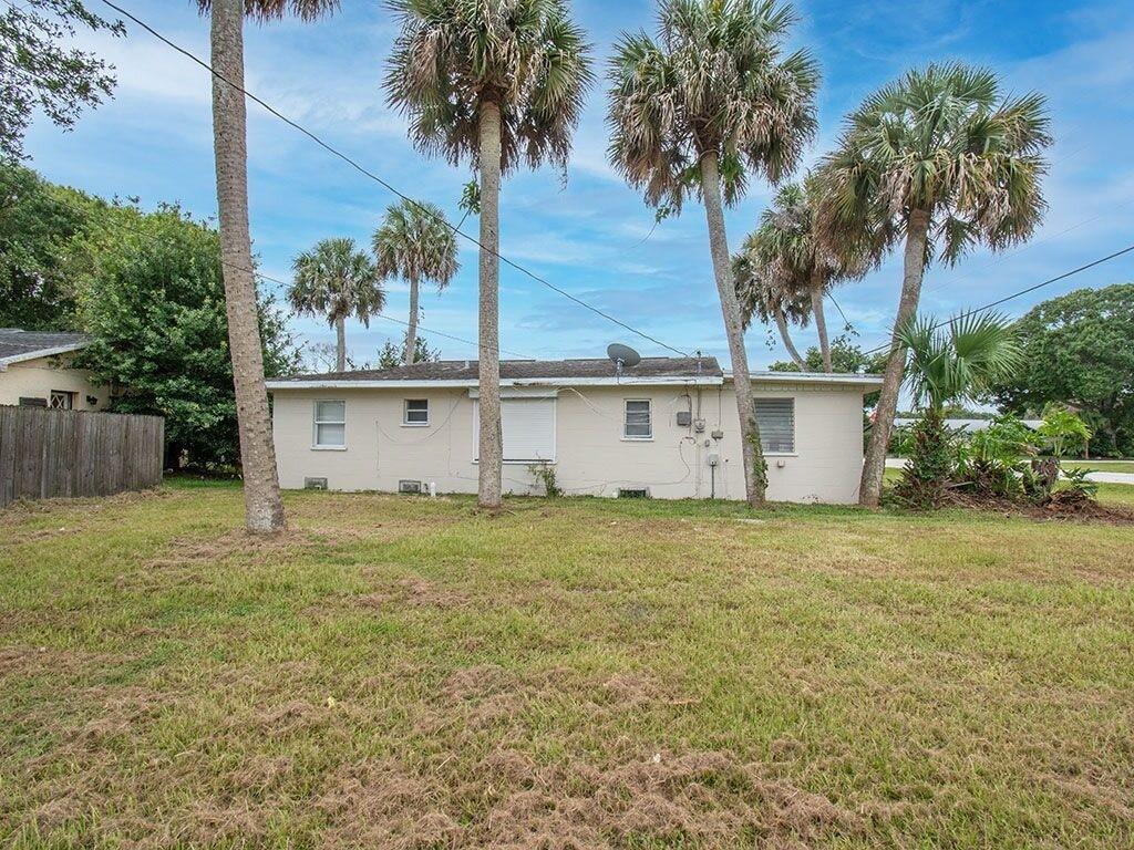 A single-story house with a beige exterior and palm trees in a grassy backyard — VERO BEACH, FL
