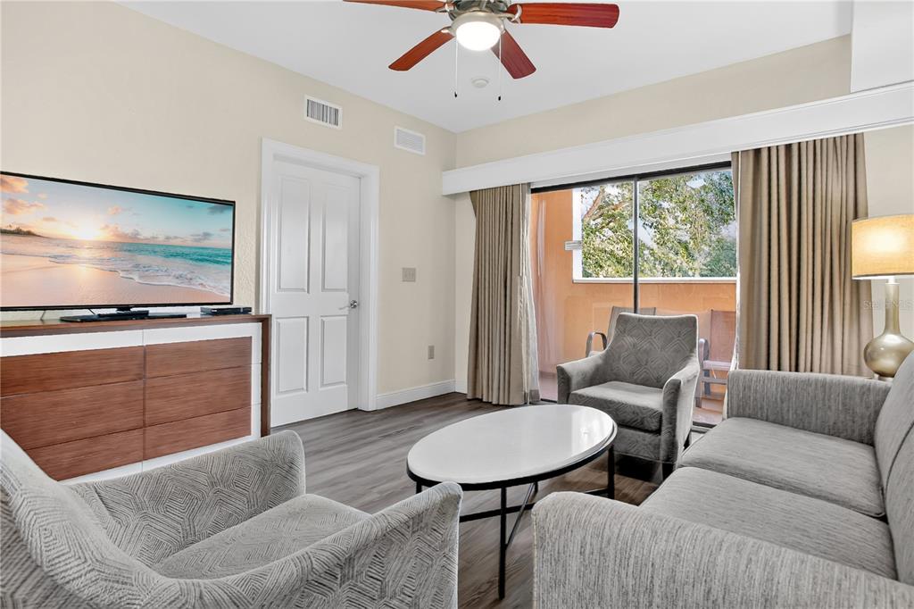 A living room features gray furniture, a white oval coffee table, and a sliding glass door — 12539 FLORIDAYS RESORT DRIVE UNIT 203D, ORLANDO, FL