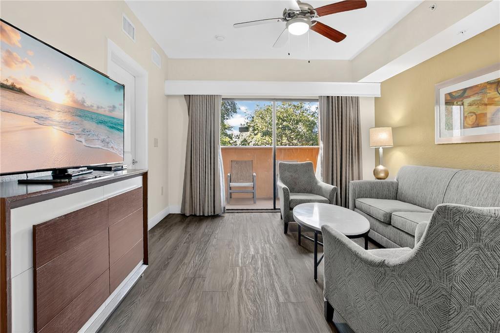 A living room features a television, gray sofa, two armchairs, and a balcony with seating — 12539 FLORIDAYS RESORT DRIVE UNIT 203D, ORLANDO, FL