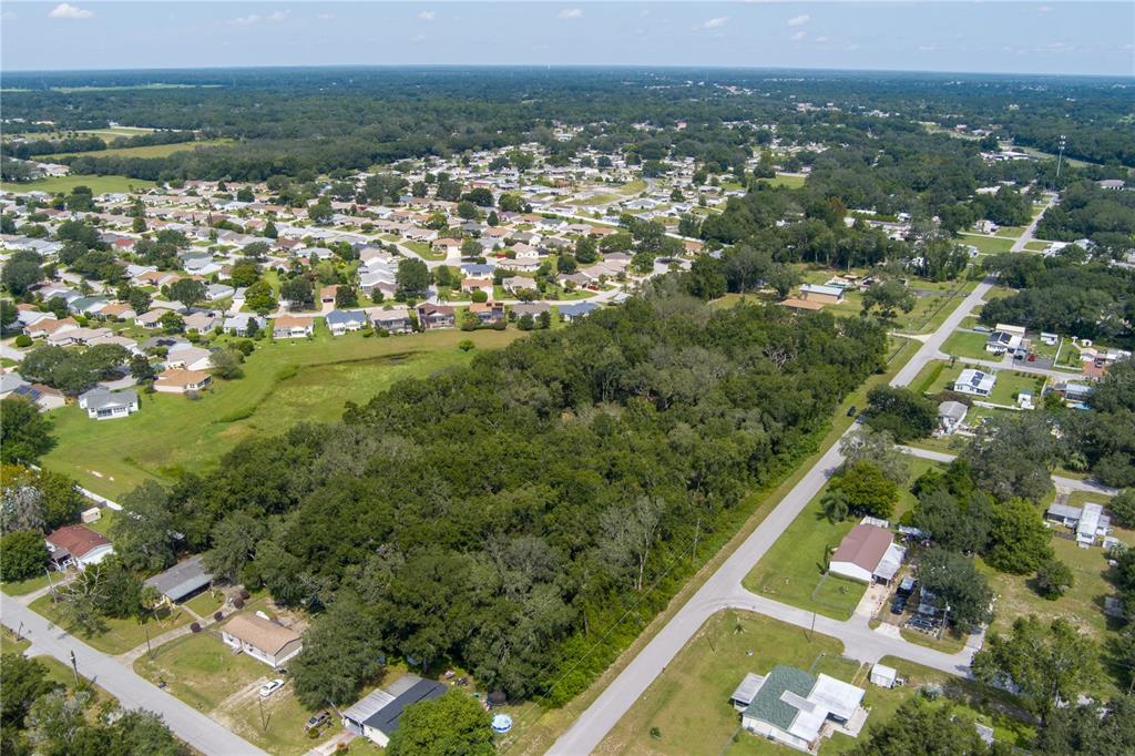 An aerial view shows a wooded lot surrounded by residential houses and paved roads — 0 SE 99TH AVENUE, SUMMERFIELD, FL