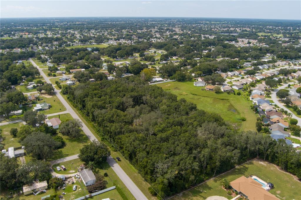An aerial view shows a large, wooded lot surrounded by residential homes and streets — 0 SE 99TH AVENUE, SUMMERFIELD, FL