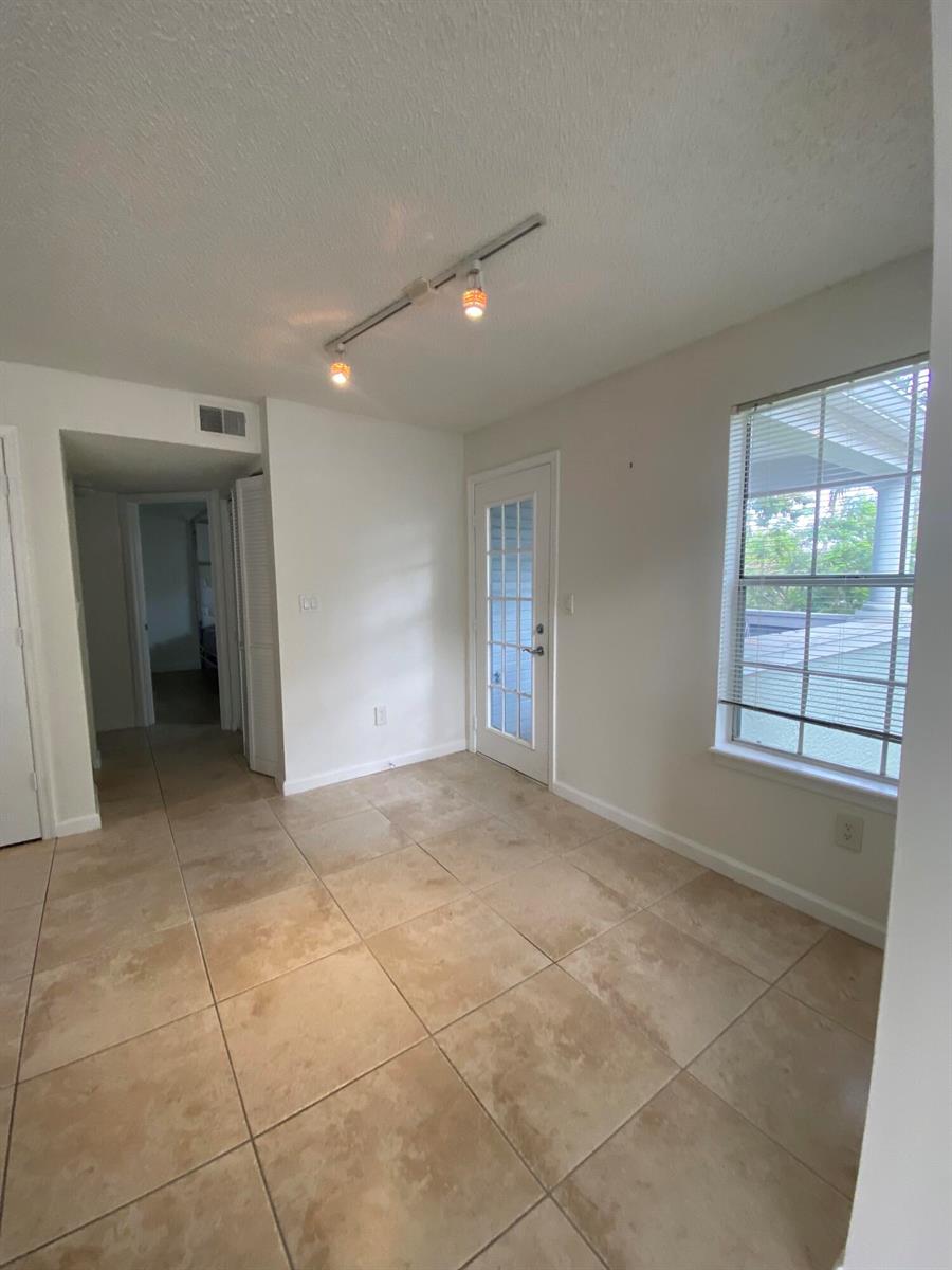 A room with beige tile flooring, a glass-paneled door, and track lighting on the ceiling — 1020 Crystal Way # H, Delray Beach FL 33444, DELRAY BEACH, FL