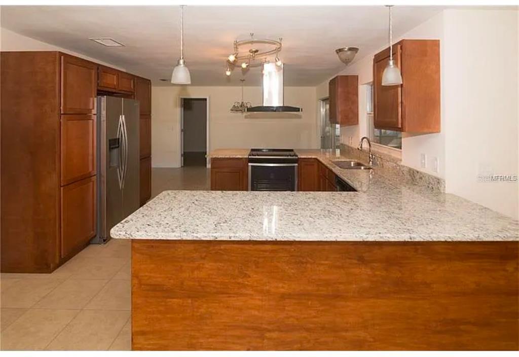 A kitchen features wood cabinets, granite countertops, stainless steel appliances, and a breakfast bar — 100 HUNTSWOOD COURT, LONGWOOD, FL