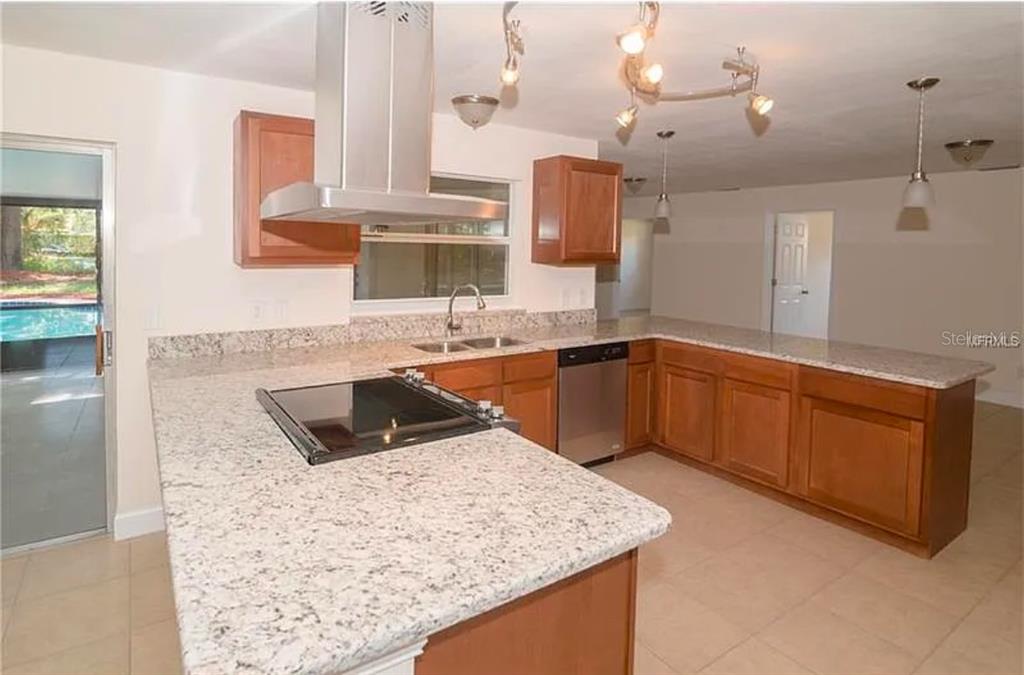 A kitchen with granite countertops, wood cabinets, a stainless steel range hood, and tile flooring — 100 HUNTSWOOD COURT, LONGWOOD, FL