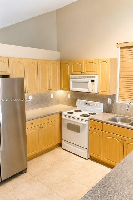 A kitchen with light wood cabinets, stainless steel refrigerator, white appliances, and tile flooring — 5420 SW 134th Ave # 0, Miramar FL 33027, MIRAMAR, FL
