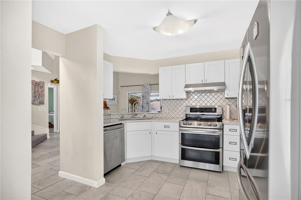 A kitchen with white cabinets, stainless steel appliances, and light-colored tile flooring — 7408 LITTLE POND COURT, ORLANDO, FL