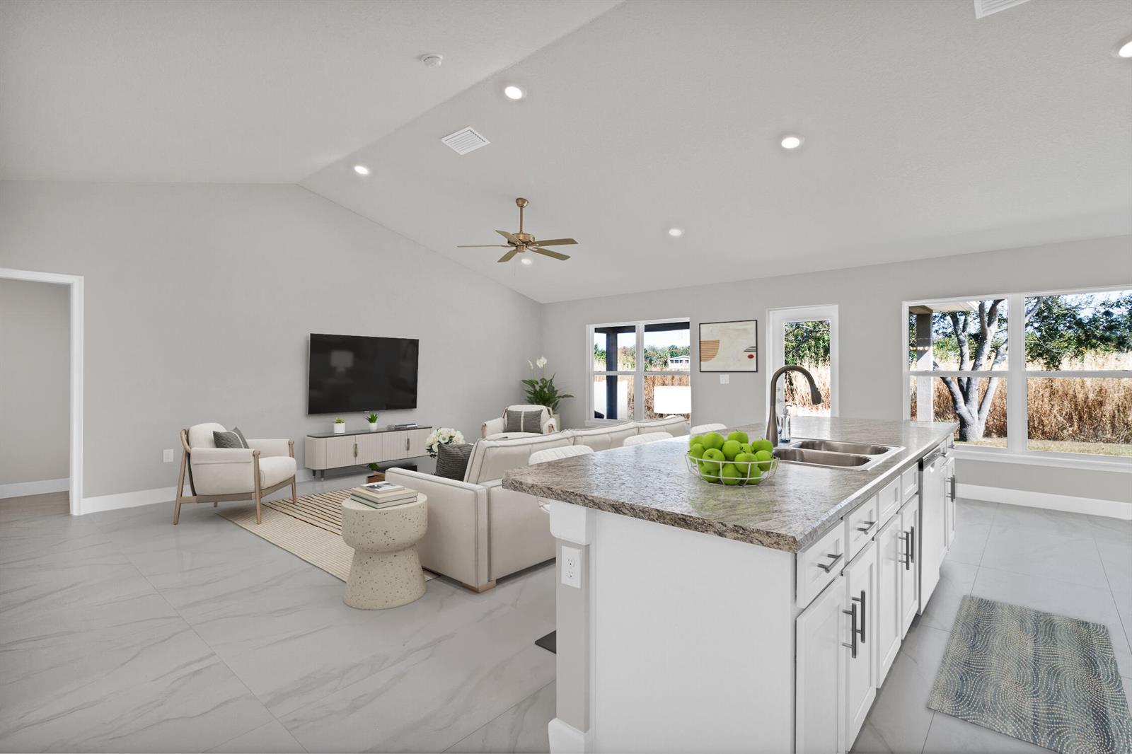 A bright, open-concept kitchen and living area featuring white cabinetry, granite countertops, and tile flooring — 170 Spring Valley Avenue, Sebastian FL 32958, SEBASTIAN, FL