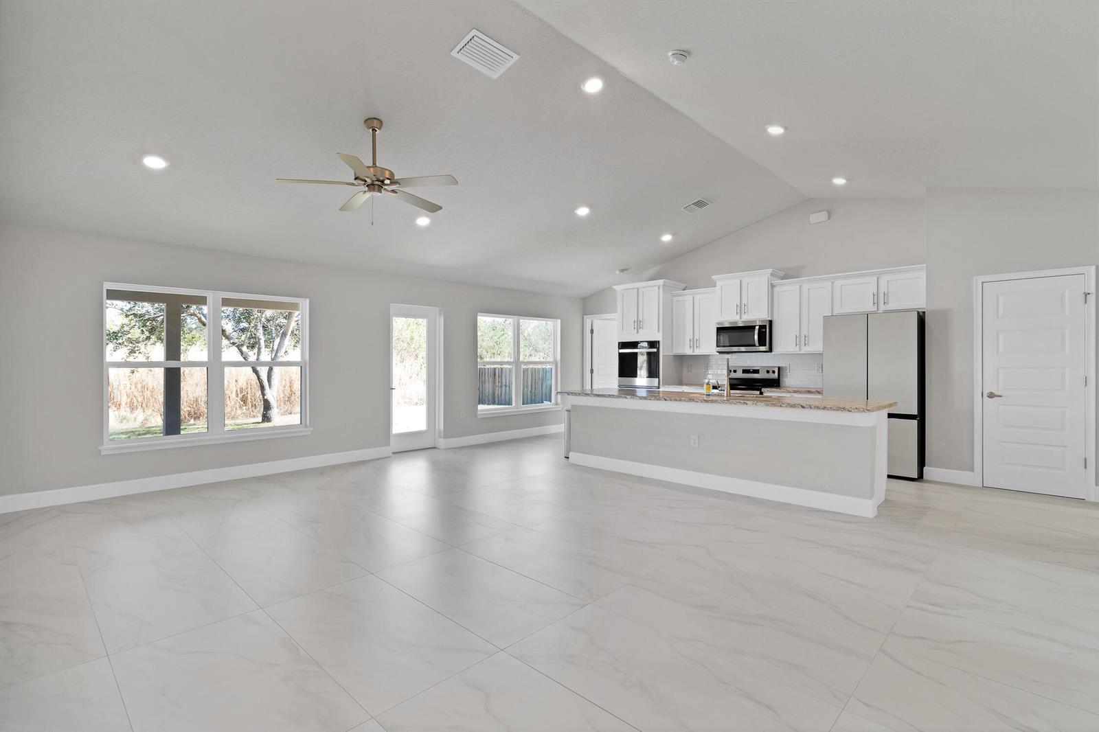 An open-concept kitchen and living area features white cabinets, stainless steel appliances, and tile flooring — 170 Spring Valley Avenue, Sebastian FL 32958, SEBASTIAN, FL