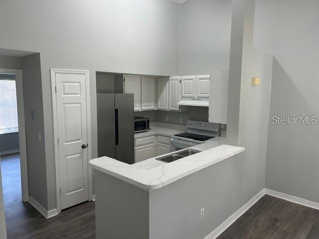 A kitchen with white cabinets, stainless steel appliances, and a marble-look peninsula countertop — 10000 SW 52ND AVENUE UNIT 158, GAINESVILLE, FL