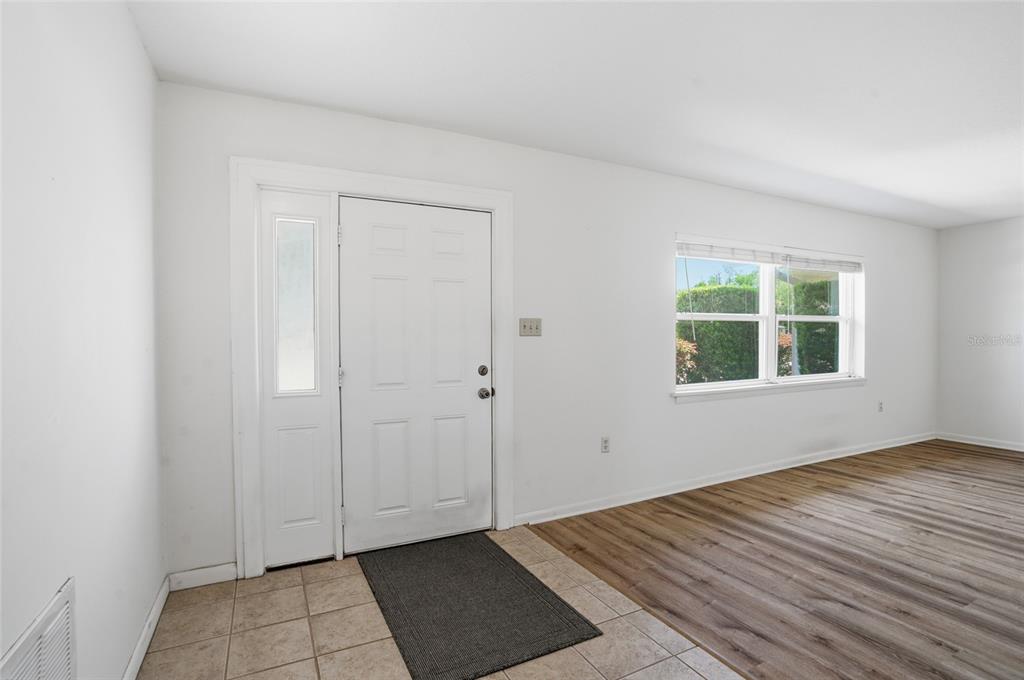 An entryway with tile flooring, a white front door, and wood-look flooring in the room — 26916 MAGNOLIA BOULEVARD, LUTZ, FL