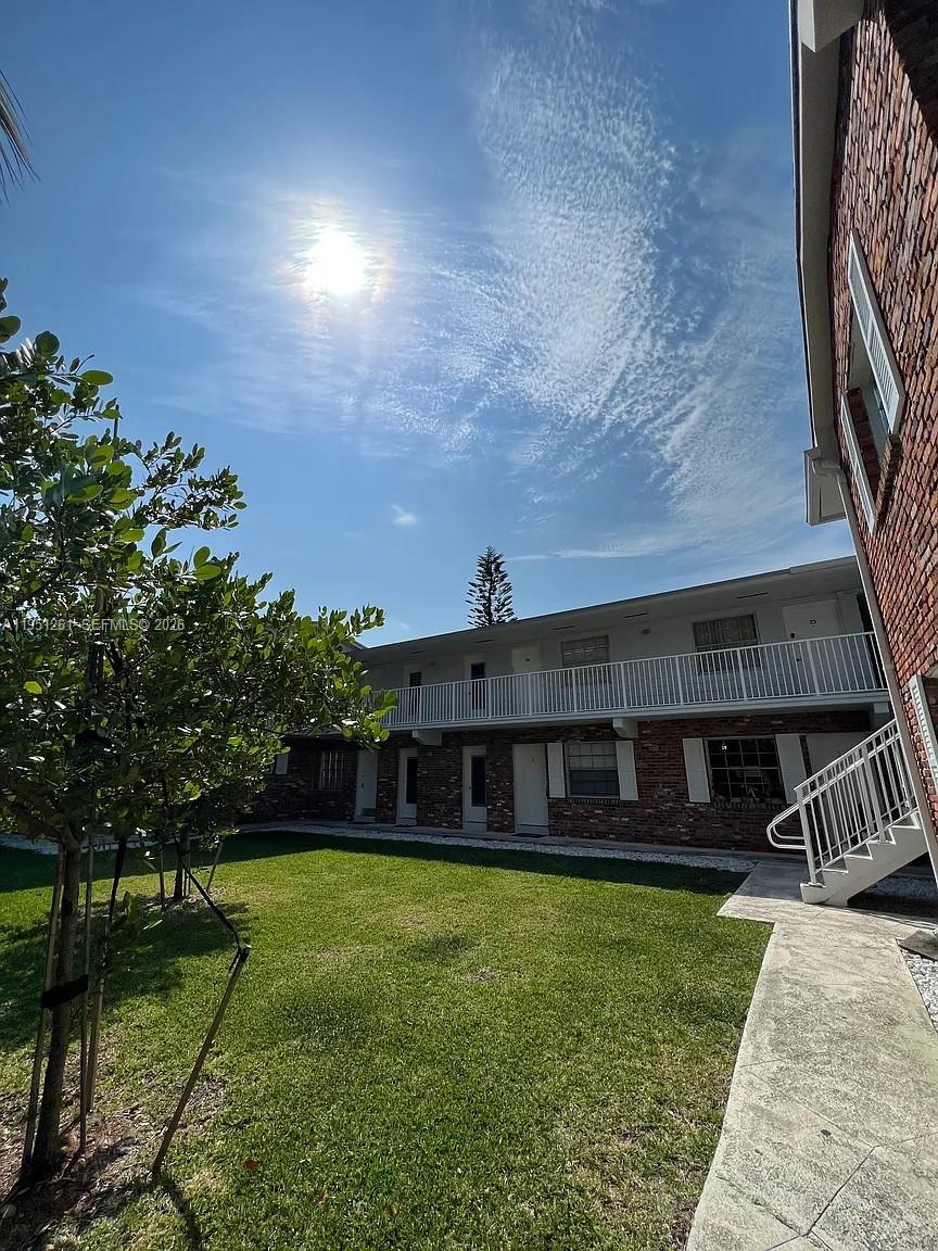 A two-story brick apartment building with a white balcony overlooks a grassy courtyard — 100 Sunrise Dr # 5, Key Biscayne FL 33149, KEY BISCAYNE, FL