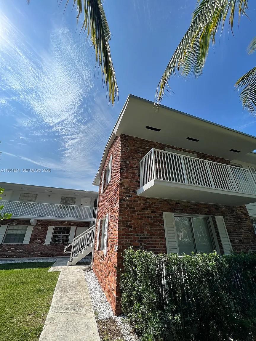 A two-story brick apartment building features white balconies and a concrete walkway — 100 Sunrise Dr # 5, Key Biscayne FL 33149, KEY BISCAYNE, FL