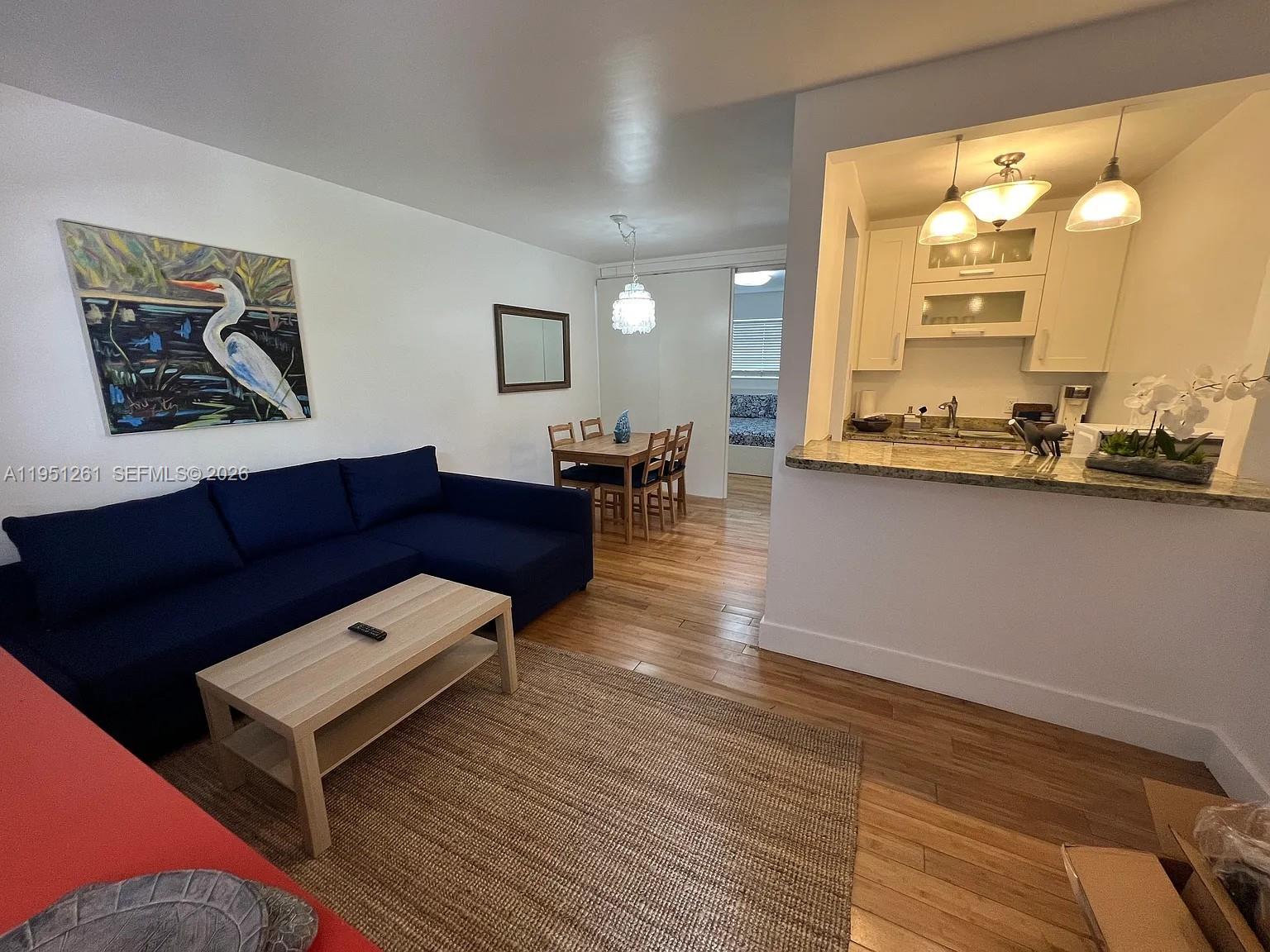 A living room with a blue sectional sofa, a dining area, and an open kitchen — 100 Sunrise Dr # 5, Key Biscayne FL 33149, KEY BISCAYNE, FL