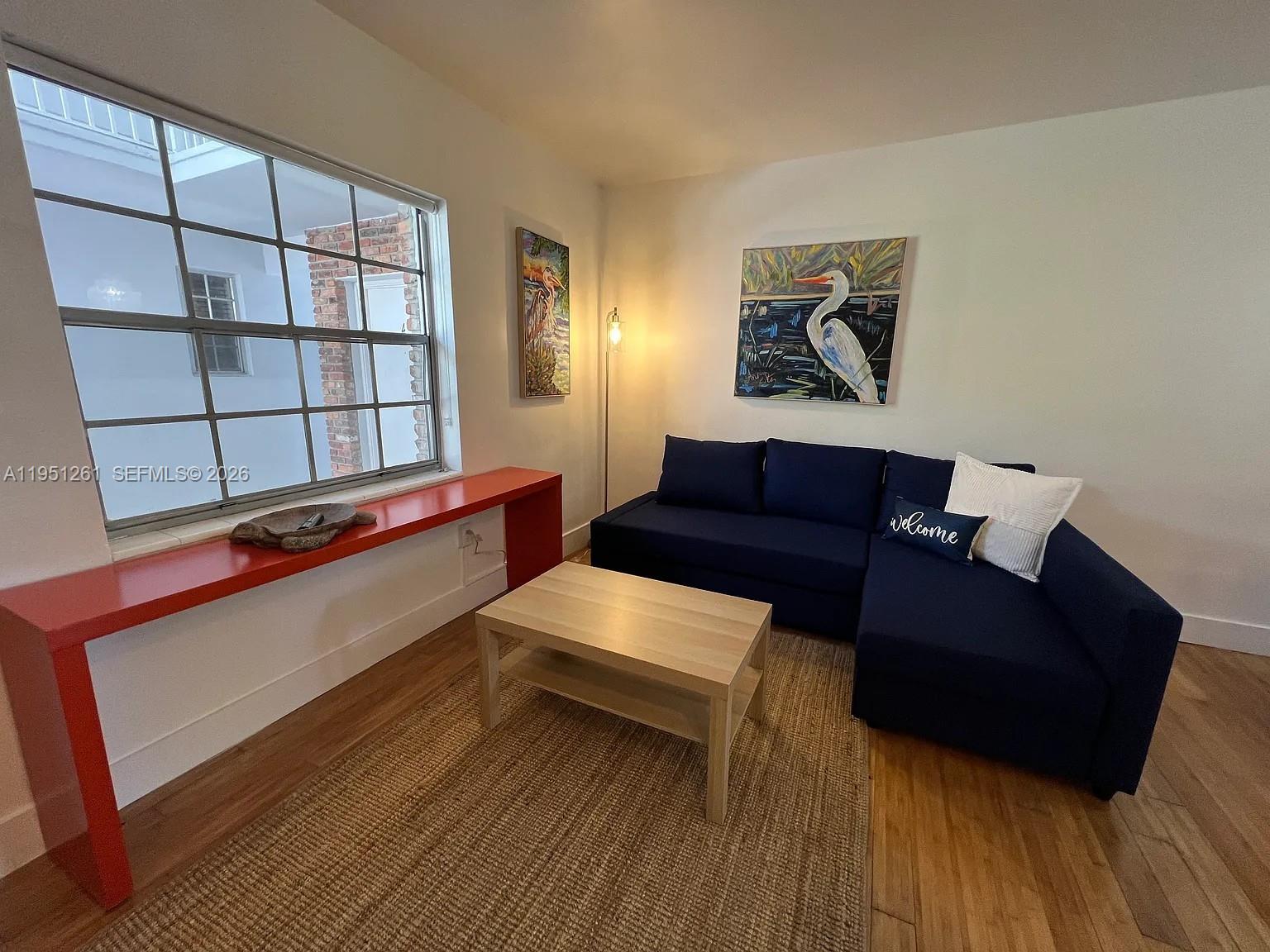 A living room features a blue sectional sofa, a coffee table, and a red console — 100 Sunrise Dr # 5, Key Biscayne FL 33149, KEY BISCAYNE, FL
