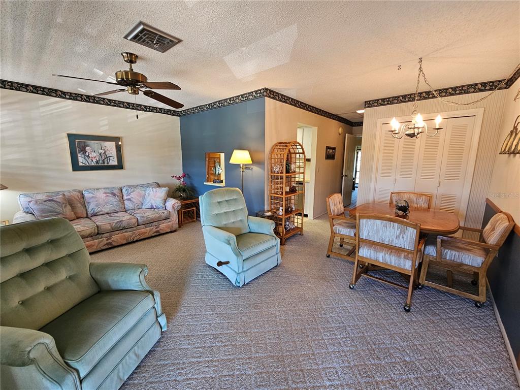 A living and dining area features carpeted floors, a ceiling fan, and light-colored walls — 6 QUAILS RUN BOULEVARD UNIT 9, ENGLEWOOD, FL