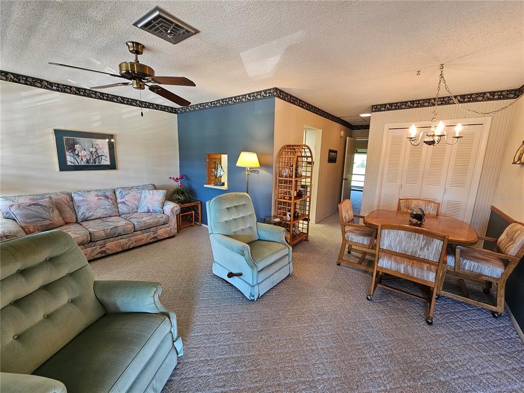 A living and dining area features carpeted floors, a ceiling fan, and a blue accent wall — 6 QUAILS RUN BOULEVARD UNIT 9, ENGLEWOOD, FL