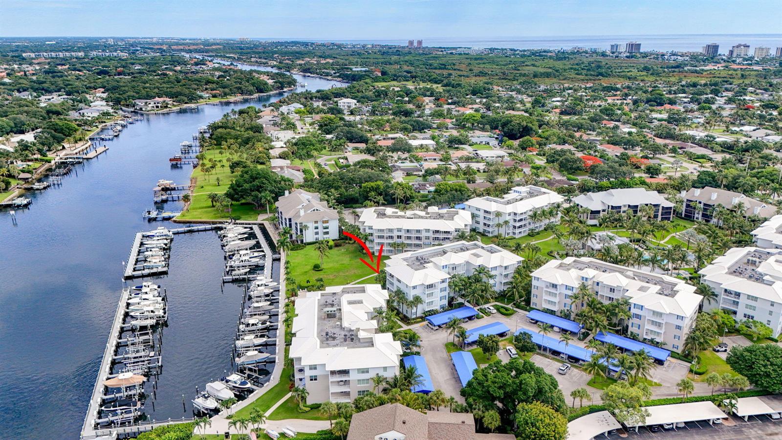 An aerial view shows a waterfront condominium complex with a boat dock and parking — 712 Bay Colony Drive S, Juno Beach FL 33408, JUNO BEACH, FL