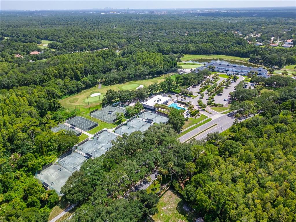 An aerial view shows a tennis complex with multiple courts, a clubhouse, and a pool — 15707 COCHESTER ROAD, TAMPA, FL