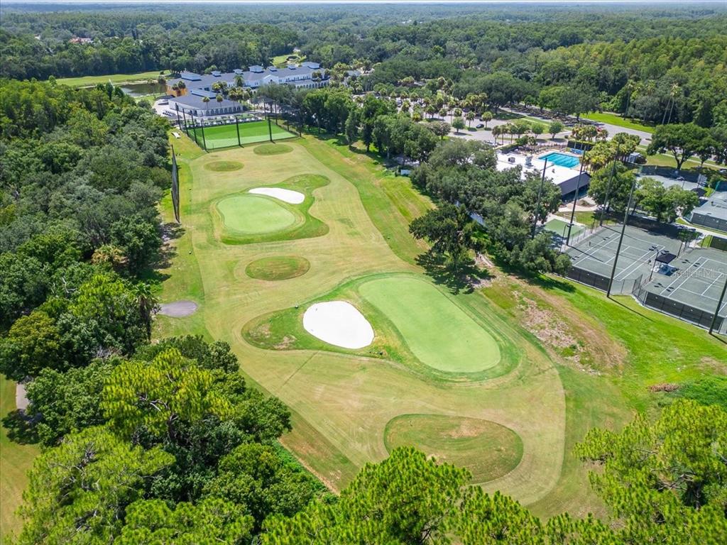 An aerial view shows a golf course fairway with sand traps, putting greens, and tennis courts — 15707 COCHESTER ROAD, TAMPA, FL