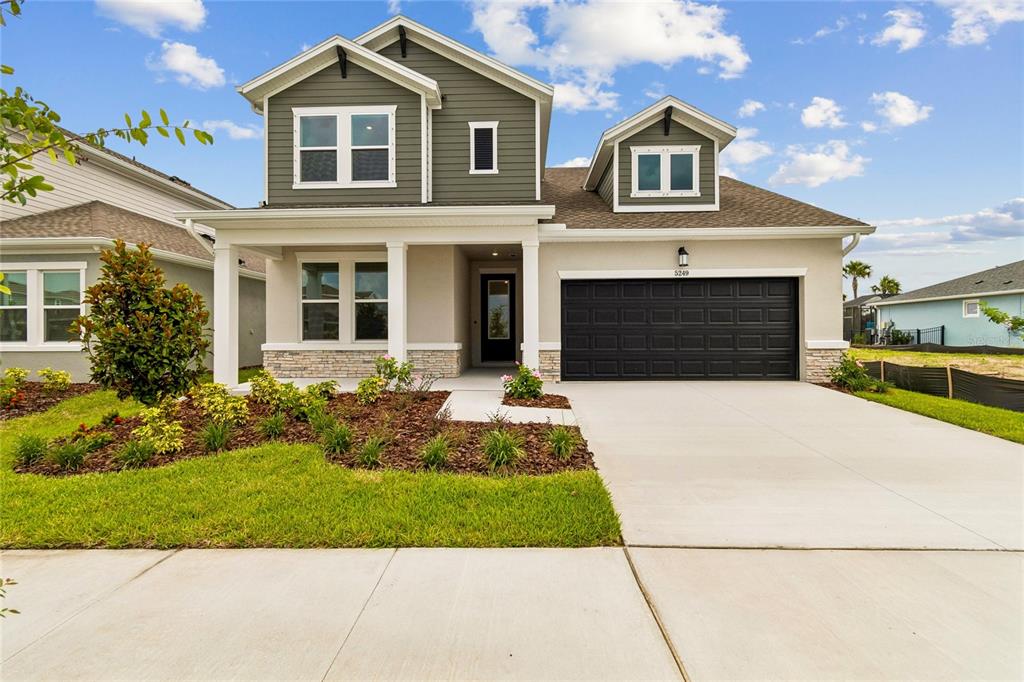 A two-story suburban house with a dark garage door, stone accents, and a front porch — 5249 EVERLONG DRIVE, APOLLO BEACH, FL