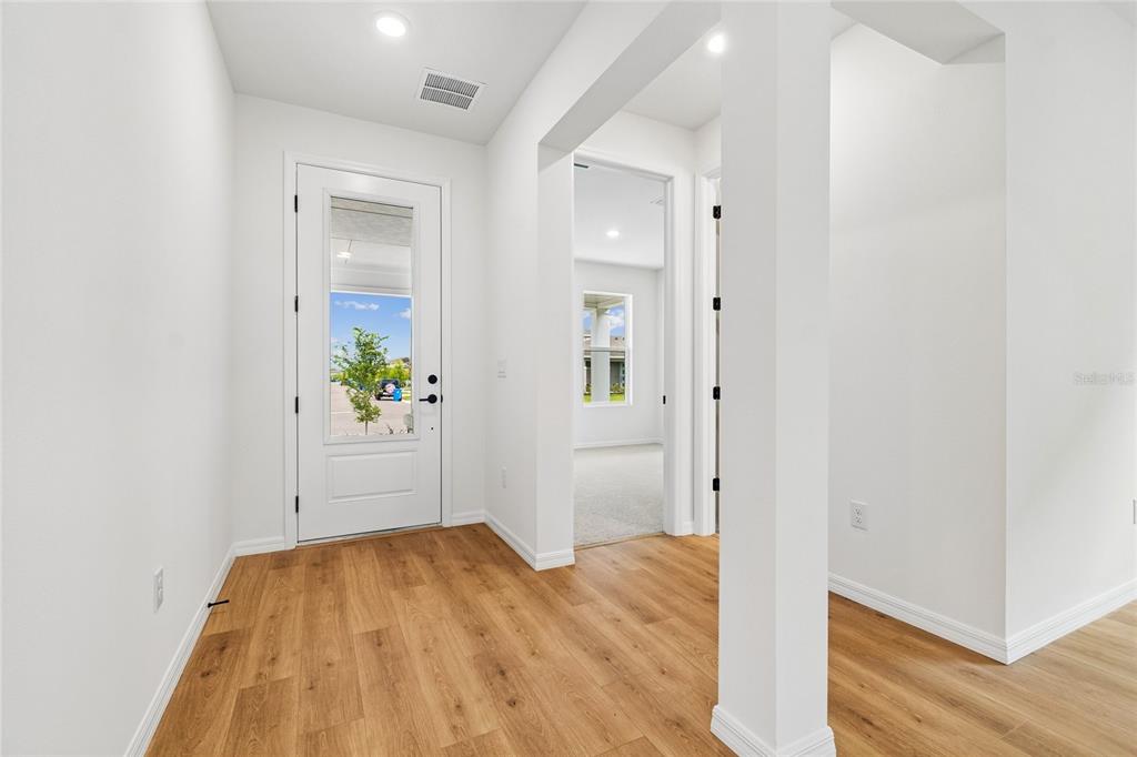 A kitchen with a central island, white cabinetry, and light wood flooring opens to a living area — 5249 EVERLONG DRIVE, APOLLO BEACH, FL