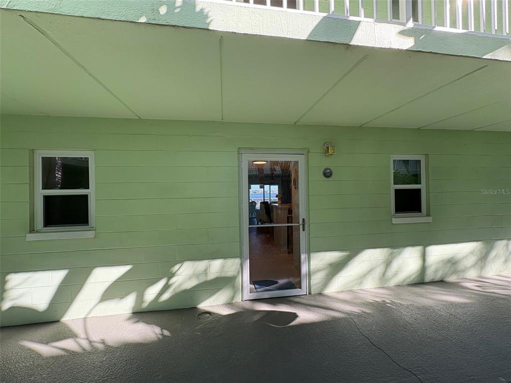 A light green exterior wall features a central glass door flanked by two windows — 464 PAULA DRIVE N UNIT 116, DUNEDIN, FL