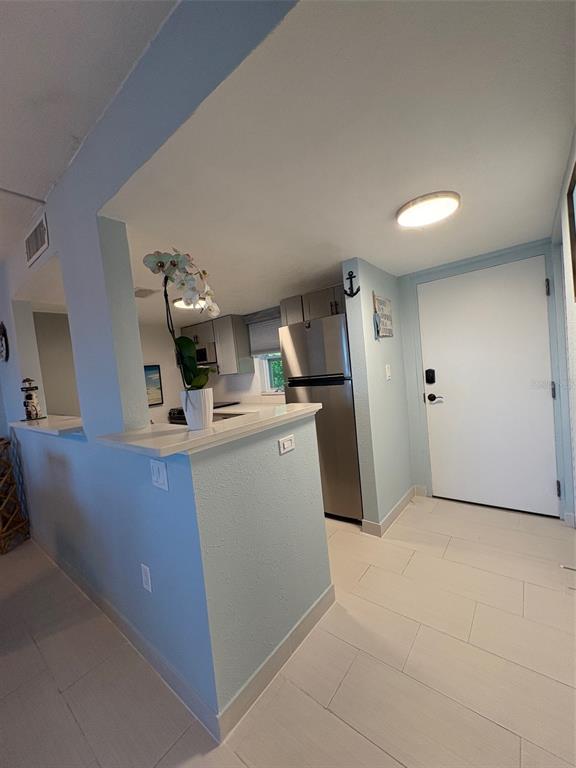 A kitchen with light blue walls, stainless steel appliances, and white tile flooring — 464 PAULA DRIVE N UNIT 116, DUNEDIN, FL