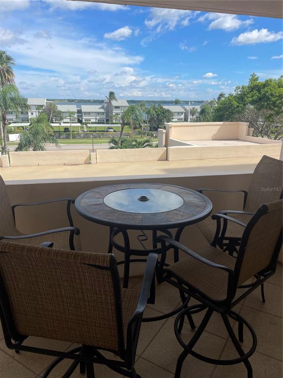 A balcony view overlooking a swimming pool, palm trees, and the ocean beach — 1270 GULF BOULEVARD UNIT 406, CLEARWATER, FL