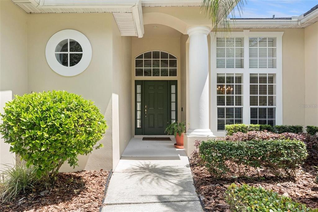 A two-story suburban house with a tan stucco exterior, green shutters, and a palm tree — 3865 WINDING LAKE CIRCLE, ORLANDO, FL