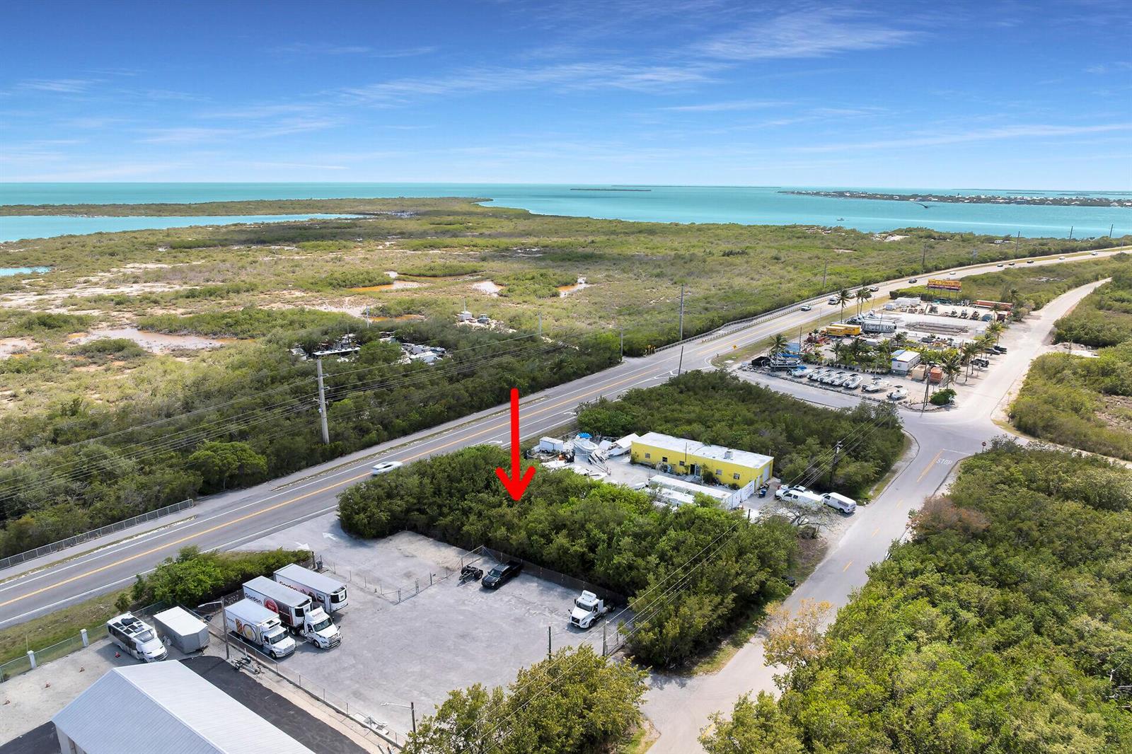 An aerial view shows a paved lot with parked trucks next to a yellow building — 26837 Overseas Highway, FL 33042, FL