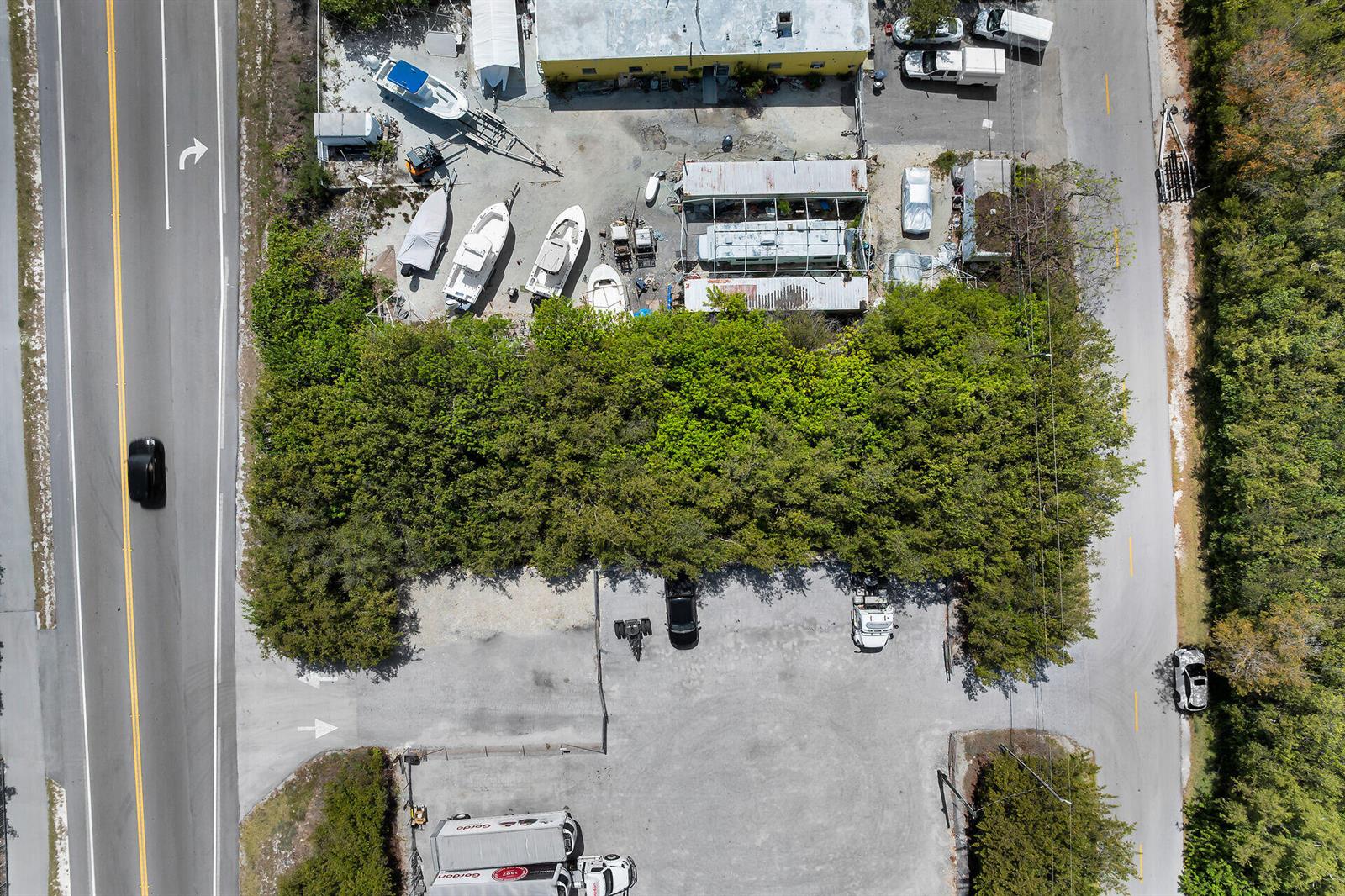 An aerial view shows a commercial lot with boats, vehicles, and a large tree line — 26837 Overseas Highway, FL 33042, FL