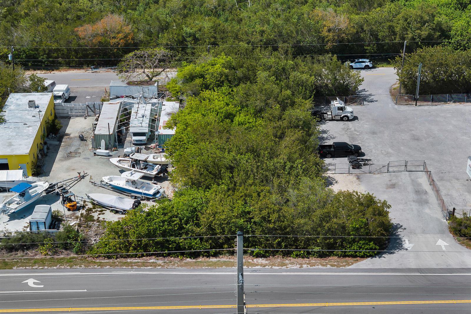 An aerial view shows a wooded lot situated between a boat storage area and a parking lot — 26837 Overseas Highway, FL 33042, FL