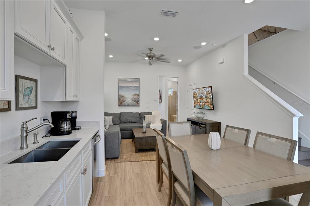 A kitchen with white cabinets and a dining area adjacent to a living room — 8061 LOST SHAKER LANE, KISSIMMEE, FL