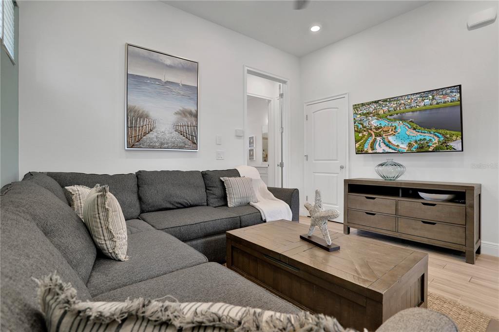 A living room features a gray sectional sofa, a wooden coffee table, and a wall-mounted television — 8061 LOST SHAKER LANE, KISSIMMEE, FL