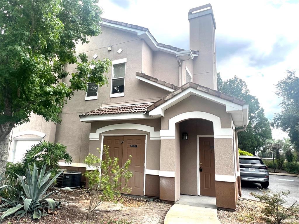 A two-story stucco building features a covered entryway, a brown door, and a storage closet — 18046 VILLA CREEK DRIVE, TAMPA, FL