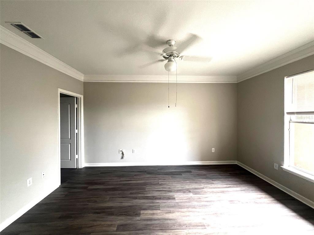 An empty room features gray walls, dark wood-look flooring, a ceiling fan, and a window — 18046 VILLA CREEK DRIVE, TAMPA, FL