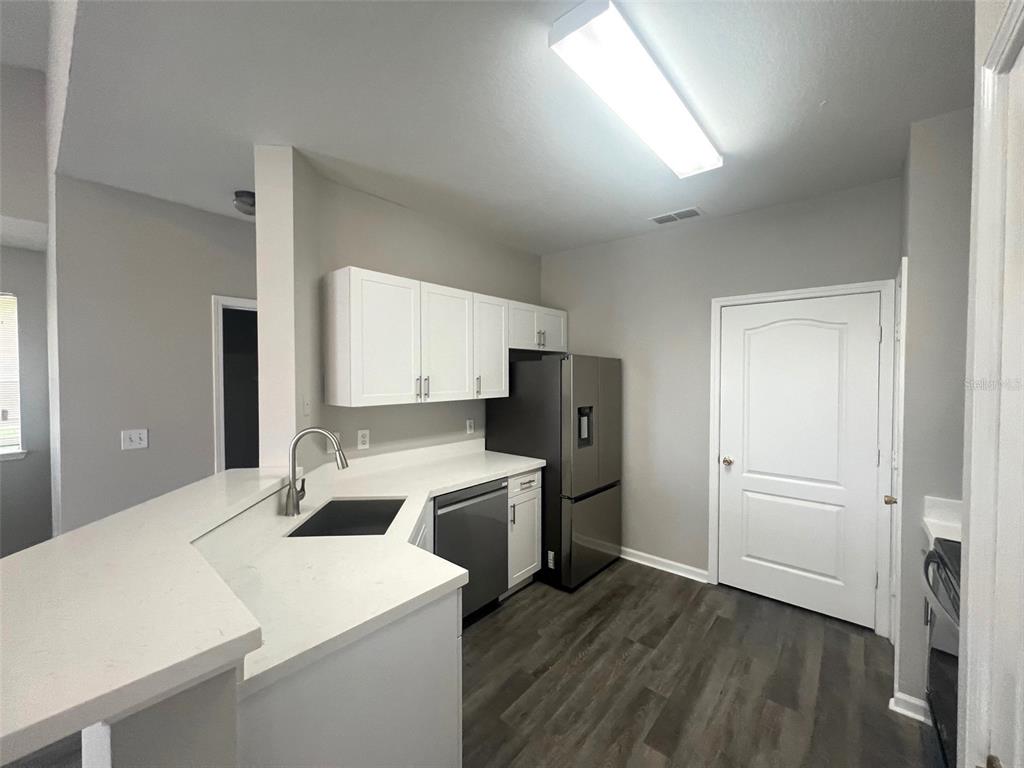 A kitchen features white cabinets, a stainless steel refrigerator, and a white countertop — 18046 VILLA CREEK DRIVE, TAMPA, FL