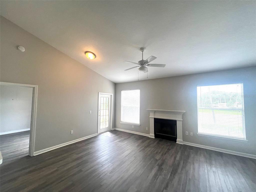 A living room with gray walls, wood-look flooring, a fireplace, and a ceiling fan — 18046 VILLA CREEK DRIVE, TAMPA, FL