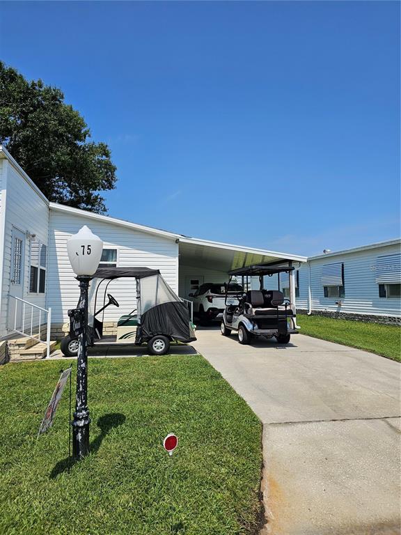 A white mobile home with a carport, two golf carts, and a decorative lamp post — 375 MELBOURN DRIVE, HAINES CITY, FL