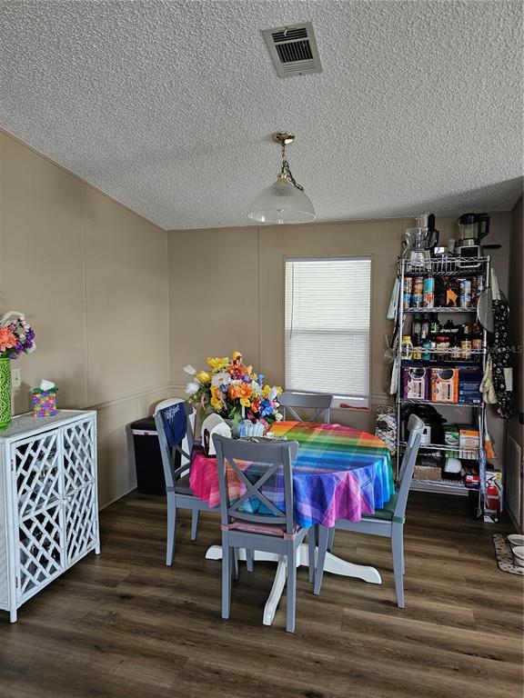 A dining area features a round table with a rainbow tablecloth, gray chairs, and metal shelving — 375 MELBOURN DRIVE, HAINES CITY, FL
