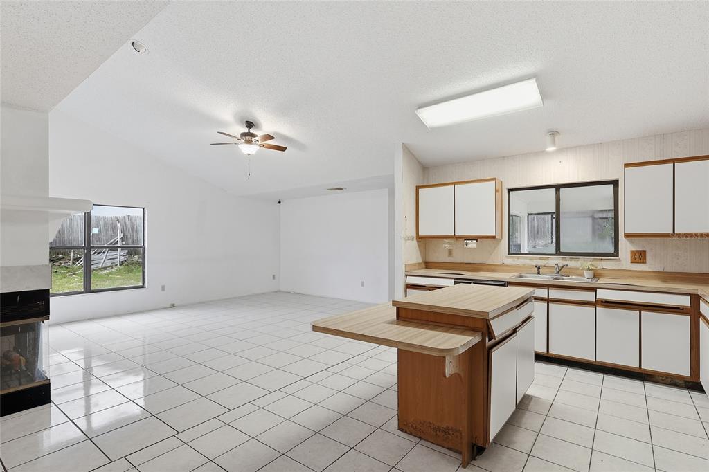 A kitchen with white cabinets and a wooden island opens into a tiled living area — 2939 DANFORTH DRIVE, ORLANDO, FL