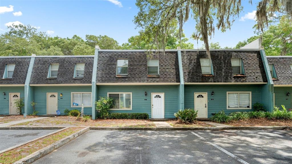 A row of teal-colored townhouses with dark shingled roofs and a parking lot in front — 501 SW 75TH STREET UNIT B5, GAINESVILLE, FL