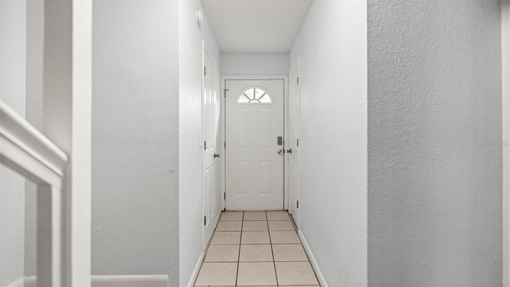A tiled entryway features a white front door and two adjacent white interior doors — 501 SW 75TH STREET UNIT B5, GAINESVILLE, FL