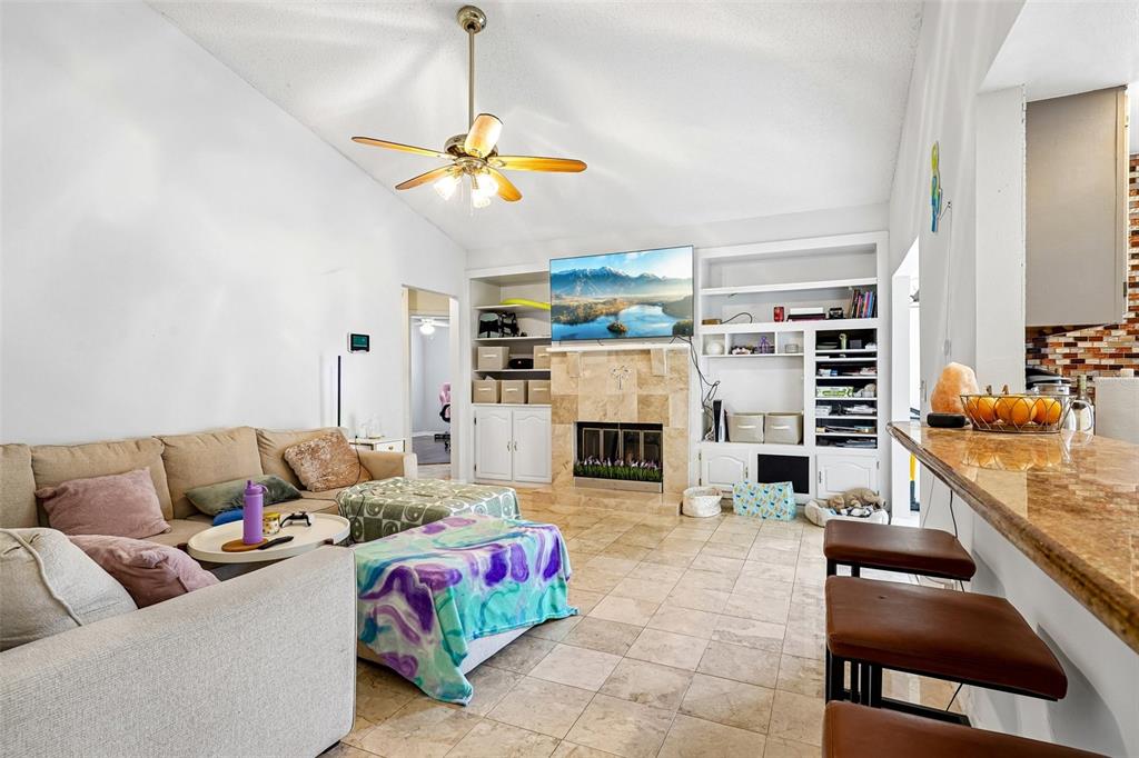 A living room features a stone fireplace, built-in shelving, tile flooring, and a ceiling fan — 1167 WOODLAND TERRACE TRAIL, ALTAMONTE SPRINGS, FL