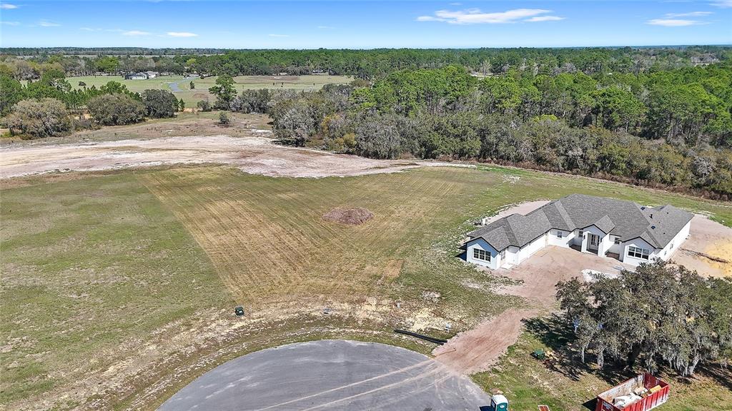 An aerial view shows a newly constructed house on a large, partially cleared rural lot — 38361 LAKE MEADOW COURT, UMATILLA, FL