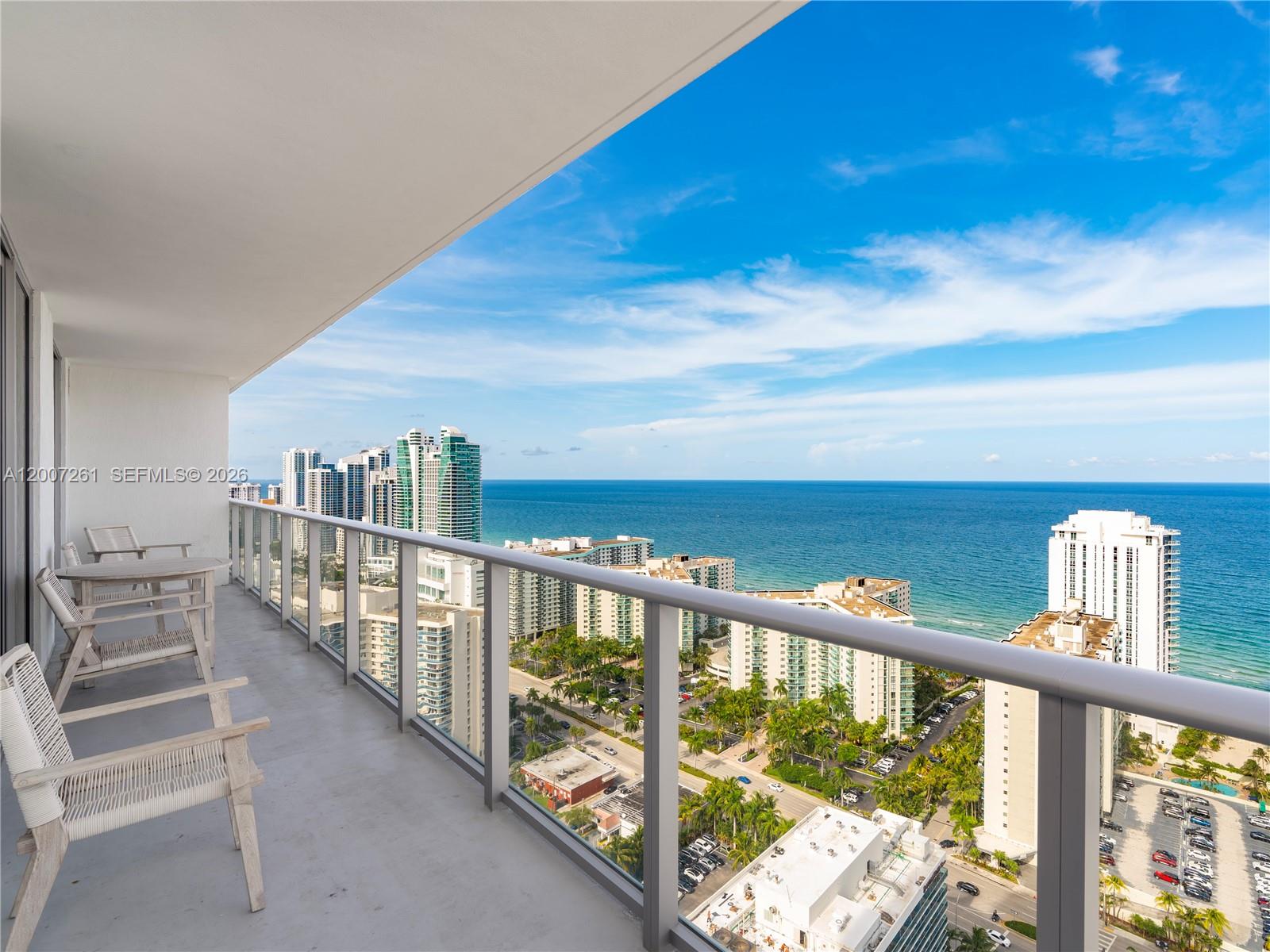 A high-rise balcony with patio furniture overlooks a coastal city and the ocean — 4010 S Ocean Dr # R2905, Hollywood FL 33019, HOLLYWOOD, FL