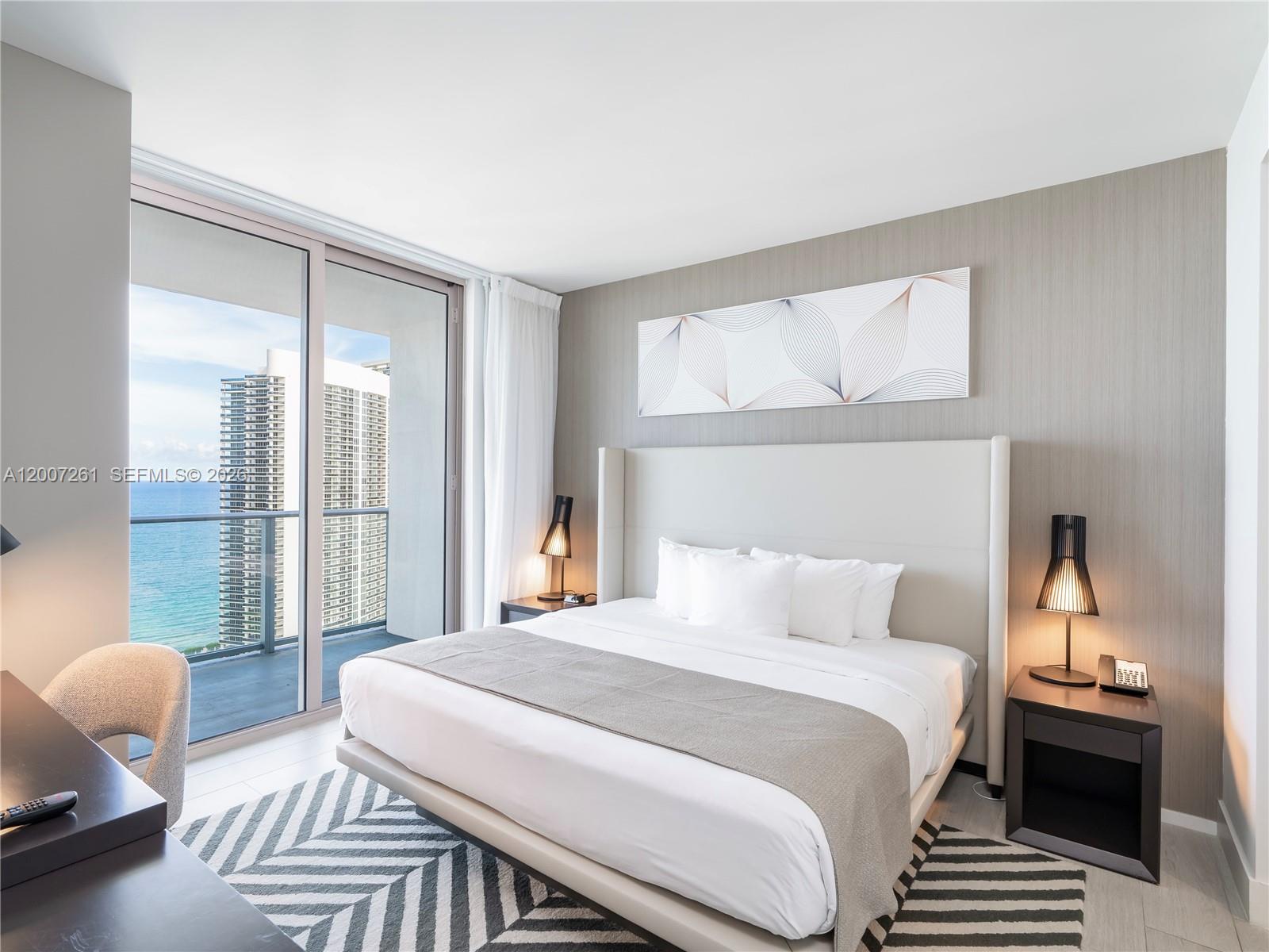 A modern bedroom features a king bed, bedside lamps, and a balcony overlooking the ocean — 4010 S Ocean Dr # R2905, Hollywood FL 33019, HOLLYWOOD, FL