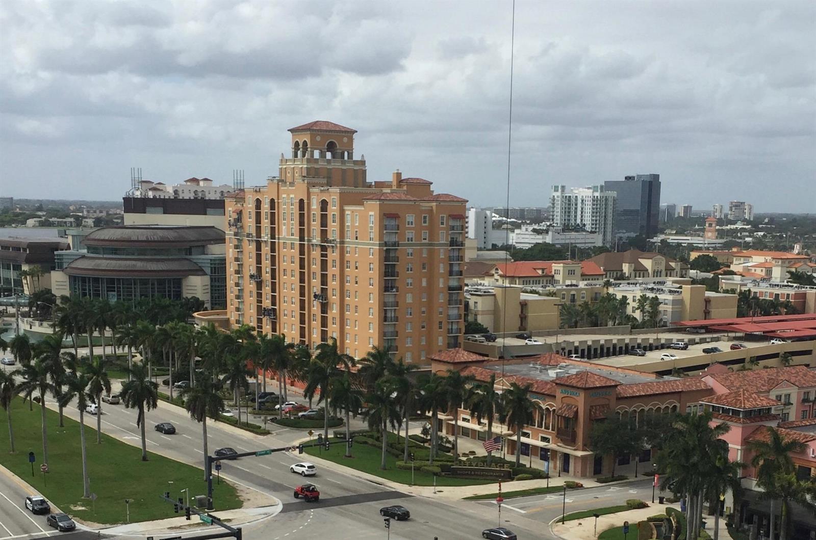 An elevated view of a multi-story tan building surrounded by palm trees and city streets — 651 Okeechobee Boulevard # 1209, West Palm Beach FL 33401, WEST PALM BEACH, FL