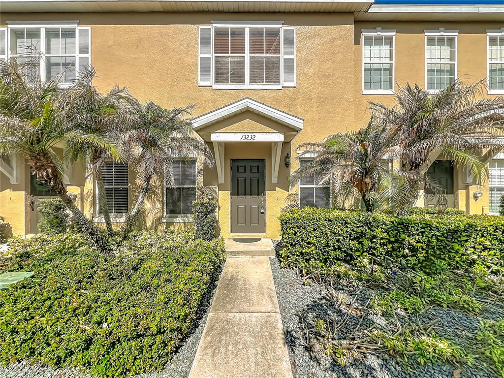A tan townhouse exterior features a central front door with a small covered entryway — 13232 DANIELS LANDING CIRCLE, WINTER GARDEN, FL