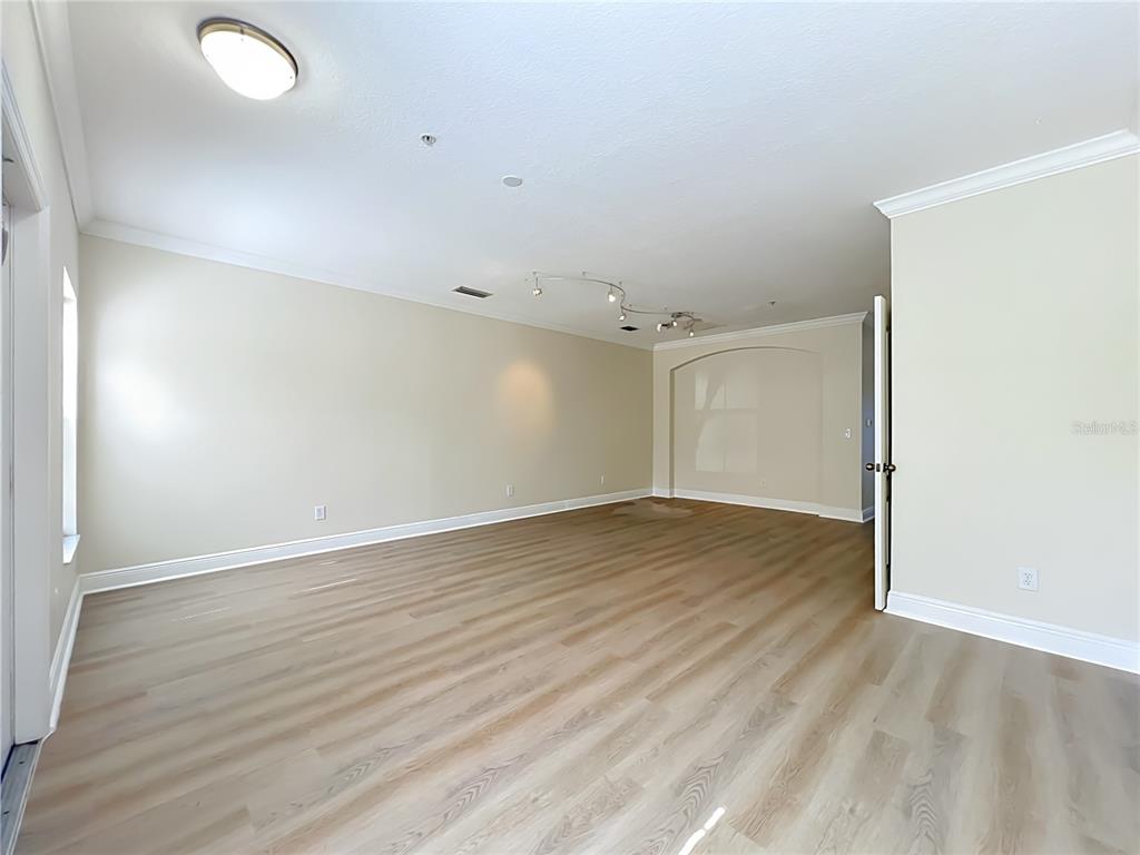 An empty room features light wood-look flooring, beige walls, crown molding, and a recessed archway — 13232 DANIELS LANDING CIRCLE, WINTER GARDEN, FL
